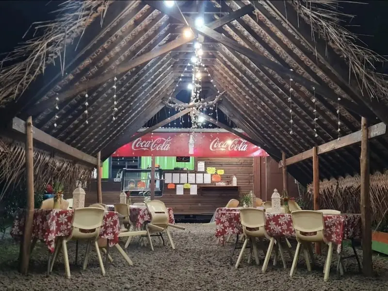 Le fare éclairé le soir, tables aux nappes à fleurs de tiare sous le toit en niau